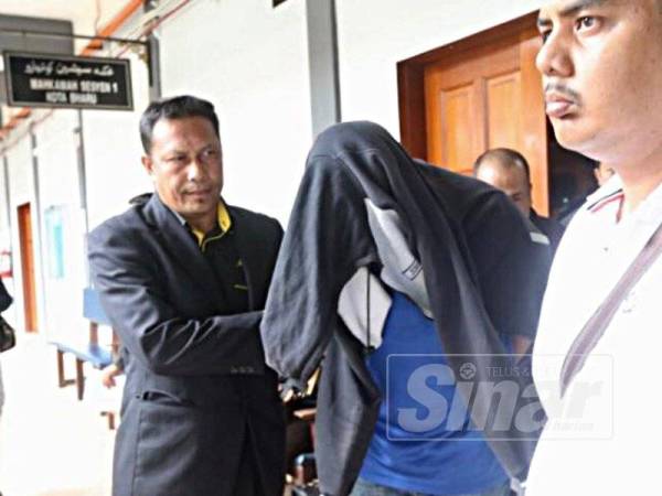 Tertuduh (tengah) dikawal anggota SPRM keluar dari Mahkamah Sesyen selepas didakwa atas pertuduhan meminta dan menerima rasuah RM2,000.