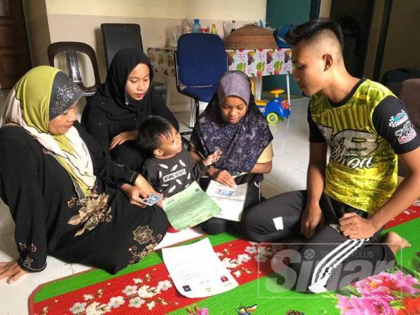 Wan Mohd Azrul (kanan) yang tidak mempunyai dokumen diri hanya mampu melihat adik-adiknya, Wan Nur Azira, Wan Muhammad Nabil dan Wan Nor Azlina memengang dokumen pengenalan diri masing-masing di samping ibu mereka Nik Rohani.