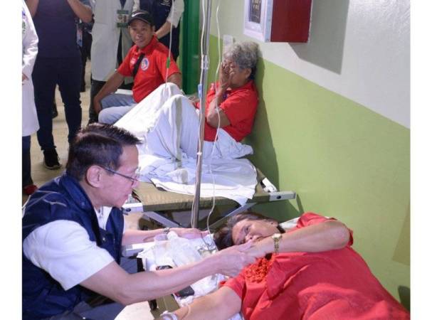 Setiausaha Kesihatan Filipina, Francisco Duque (kiri) melawat seorang pesakit di wad kecemasan sebuah hospital di Manila yang dipercayai keracunan makanan ketika menghadiri sambutan hari jadi Imelda Marcos hari ini. - Foto AFP