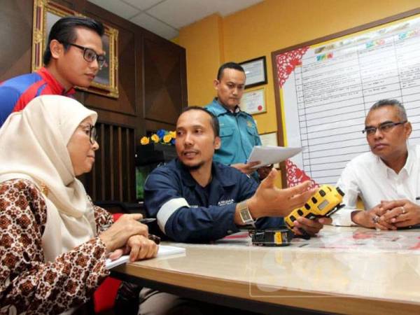 Pengarah JAS Johor, Wan Abdul Latiff Wan Jaafar (kanan) melihat penerangan penggunaan alat pengesanan gas kepada pihak sekolah.