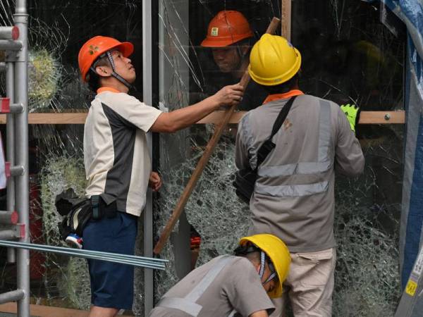 Pekerja sedang membaik-pulih pintu kaca di bangunan Parlimen yang musnah akibat dipecahkan kumpulan penunjuk perasaan. - FOTO AFP