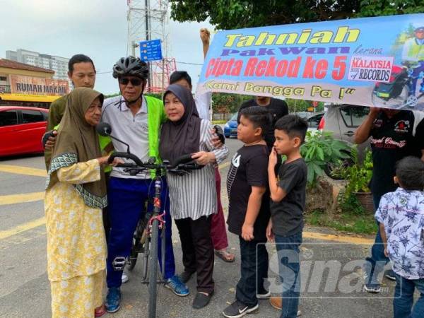 Pak Wan (tengah) disambut ibu, isteri dan cucunya didepan rumahnya di Telipot di sini.