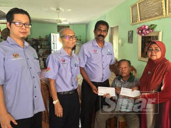 Anthony (tengah) menyampaikan cek kepada Abdul Rahman dan Zainab di kediaman mereka di Kampung Tanjung Tualang semalam.