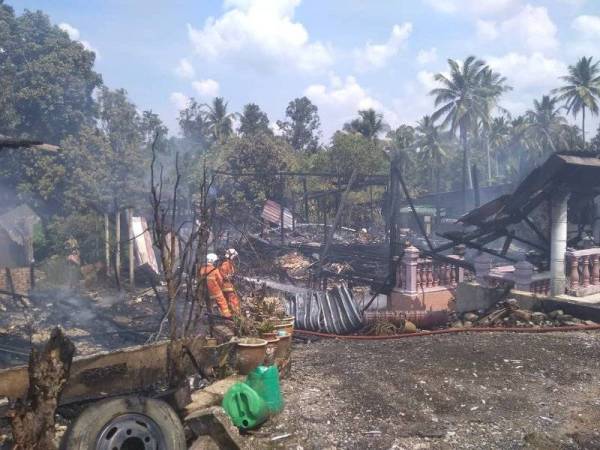 Anggota bomba berusaha memadamkan sisa api dalam kebakaran yang memusnahkan dua rumah di Felda Jerangau, Dungun.