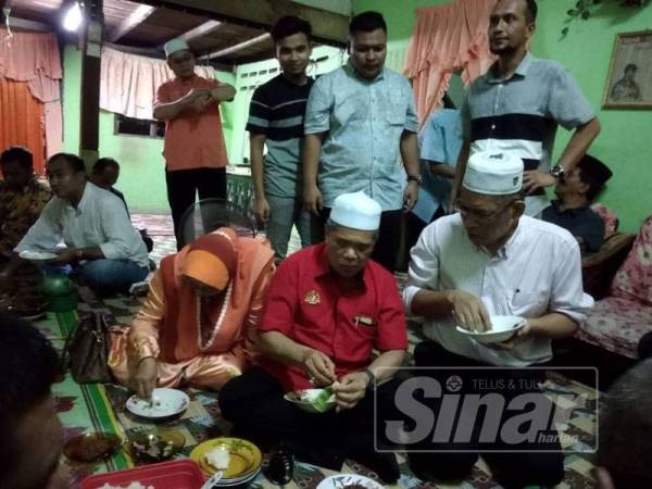 Mohamad Sabu (duduk, tengah) menikmati pulut nyior sambil diperhatikan Mohd Hanif berdiri (tengah).