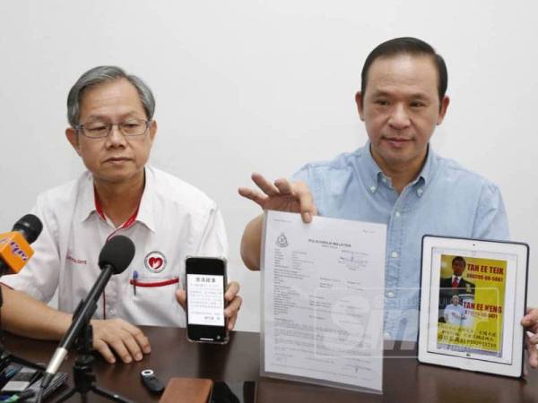 Ee Keng menunjukkan laporan polis dan poster yang ditampal oleh ah long sambil diperhatikan oleh Boon Chye (kiri) pada sidang media di Pusat Khidmat Ahli Parlimen Gopeng di sini hari ini.