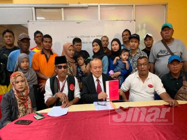 Kamarudin (duduk, tengah) bersama mangsa yang terjejas akibat pencemaran Sungai Kim Kim pada Mac lalu, bergambar bersama pada sidang media berkenaan hari ini.