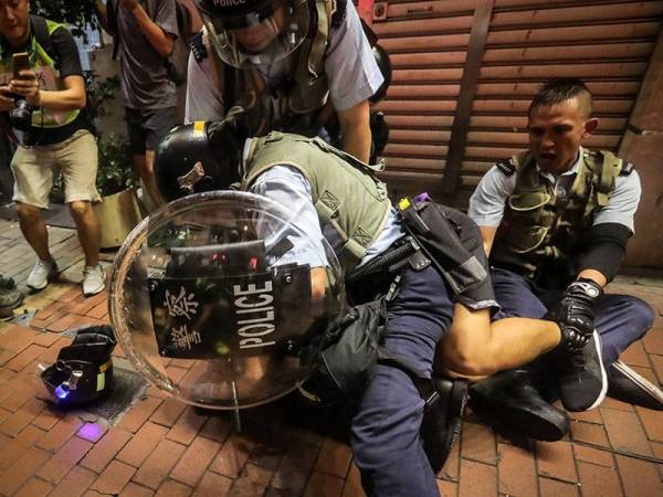 Salah seorang penunjuk perasaan bergelut dengan pihak berkuasa ketika protes di bandar raya Hong Kong semalam. 