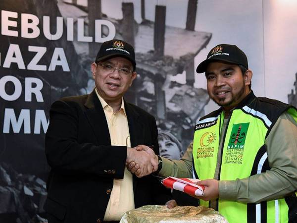 Menteri Luar Datuk Saifuddin Abdullah menyerahkan Jalur Gemilang kepada Ketua Pegawai Eksekutif Majlis Perundingan Pertubuhan Islam Malaysia (Mapim) Dr Ahmad Sani Abdul Alim Araby pada sesi Flag Off Misi Kemanusiaan 'Rebuild Gaza For Ummah' oleh Mapim di Lapangan Terbang Antarabangsa Kuala Lumpur hari ini. - Foto BERNAMA