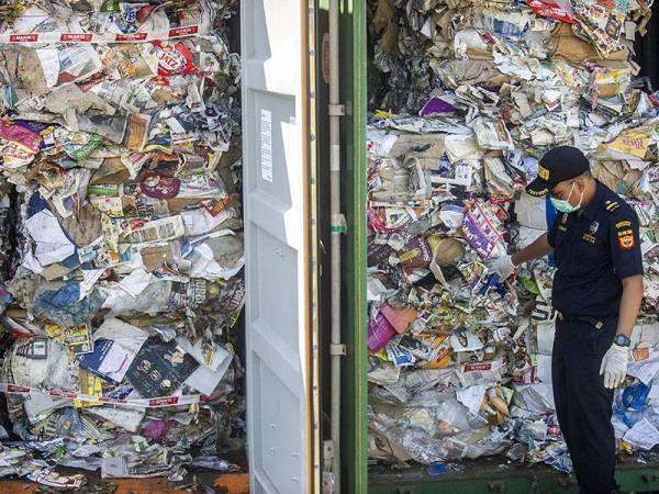 Seorang pegawai kastam memeriksa sisa sampah dari Australia yang dirampas di bandar Surabaya.