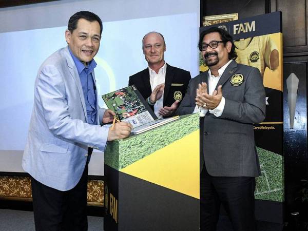 Presiden Persatuan Bola Sepak Malaysia (FAM) Datuk Hamidin Mohd Amin (kiri) menandatangani Buku Pelancaran Majlis DNA Bola Sepak Malaysia hari ini. - Foto BERNAMA