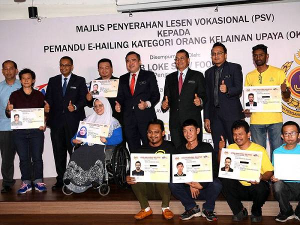 Menteri Pengangkutan Anthony Loke Siew Fook (berdiri empat, kanan) bergambar bersama para penerima lesen Orang Kurang Upaya (OKU) pada Majlis Penyerahan Lesen Kenderaan Pengangkutan Awam (PSV) kepada Pemandu E-hailing Kategori OKU di First Avenue, Petaling Jaya hari ini. - Foto BERNAMA