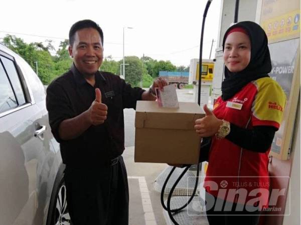 Hamid (kanan) menunjukkan kupon RM1 bagi pembelian petrol RM50 untuk membantu SDAHA di sebuah stesen minyak di Jalan Johor kelmarin.