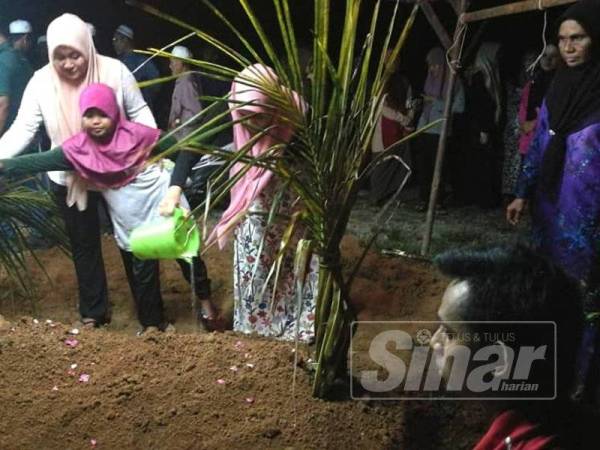 Halimah (kanan) bersama anak-anak yang lain di kubur Nur Syafiqah sebaik selesai urusan pengebumian di sini malam ini.