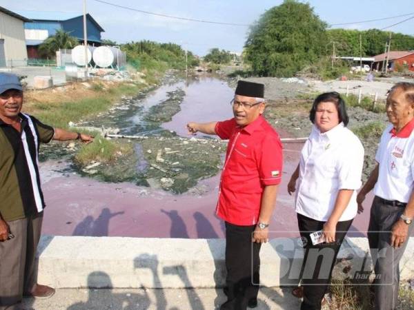 Abdul Aziz (tiga dari kanan) menunjukkan parit di Kampung Baru Sungai Tiang, Bagan Datuk bertukar warna merah jambu ketika lawatannya hari ini.