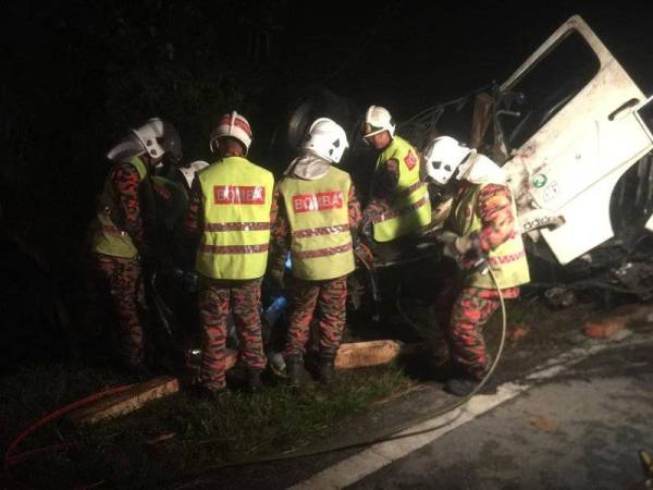 Anggota bomba bertungkus-lumus mengeluarkan mayat mangsa tersepit di bahagian hadapan tempat pemandu lori di Kilometer 48, Lebuhraya Timur Barat Gerik-Jeli, Gerik malam semalam.