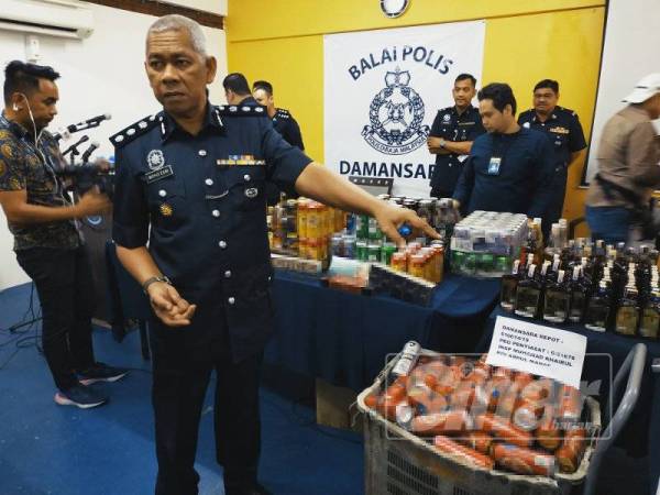 Mohd Zaini Che Din menunjukkan arak dan rokok yang dirampas dalam dua serbuan berasingan.