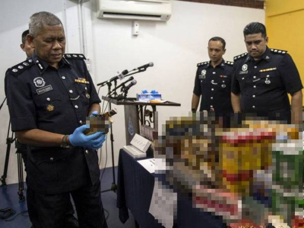 Ketua Polis Daerah Petaling Jaya ACP Mohd Zani Che Din (kiri) memeriksa barangan yang dirampas pada sidang media di Balai Polis Damansara hari ini. Ekoran dari dua serbuan yang dilakukan pihak Polis Ibu Pejabat Daerah Petaling Jaya telah merampas barangan merupakan 607 tin dan botol minuman arak pelbagai jenama dan 32 karton rokok tiruan disyaki seludup yang dianggarkan bernilai RM10,490. - Foto Bernama 