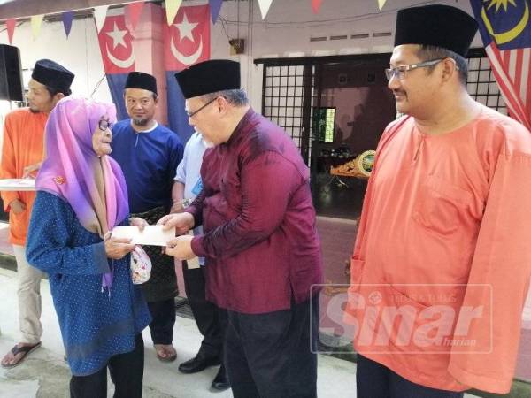 Aminolhuda (dua dari kanan) menyerahkan sumbangan kepada warga emas pada Majlis Jamuan Jalinan Ukhuwah di Kampung Tengah Renggam, Kluang hari ini.