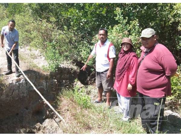 Mohd Yahya (kiri) menunjukkan jarak rekahan yang berlaku di benteng pemecah ombak di Kampung Tampok Laut, Benut sambil diperhatian Azmi (tiga dari kanan) dan Norlizah (dua dari kiri).