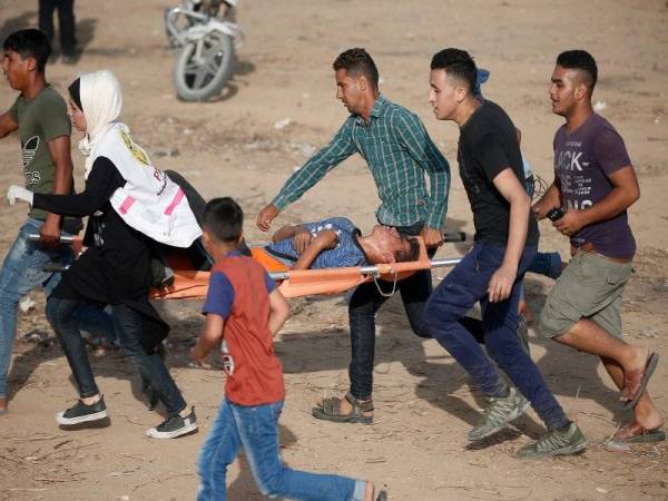 Anggota paramedik dan penduduk Palestin mengusung seorang mangsa yang cedera semasa protes 'Great March of Return' di sempadan Gaza semalam.