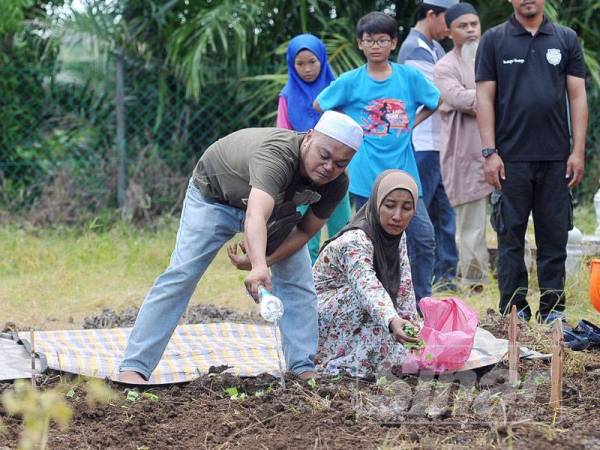 Mohd Fakrul Khair Bahrin,41 dan Serihayati Ngainan,48, menyiram air dan menabur bunga ke atas pusara kedua-duanya yang telah selamat dikebumikan di Tanah Perkuburan Islam Kampung Endah. - FOTO ROSLI TALIB