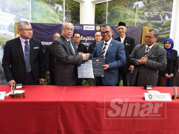 Hassan Basri (kanan) dan Azemi (kiri) bertukar dokumen selepas majlis menandatangani MOU antara UniSZA dan Arkib Negara Malaysia hari ini.