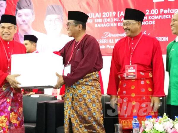 Jahaya (kanan) menyampaikan cenderahati kepada Naib Presiden UMNO, Datuk Seri Mohamed Khaled Nordin (dua, kiri) pada Mesyuarat Perwakilan UMNO Bahagian Kuala Selangor di Dewan Dato Seri Dr Abu Hassan Omar Kompleks UMNO Bahagian Kuala Selangor, di sini hari ini.