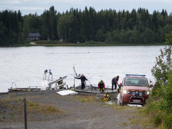 Bot pasukan kecemasan membawa serpihan pesawat kecil yang terhempas di Umea, Sweden semalam ke sebuah pelabuhan kecil. - Foto AFP