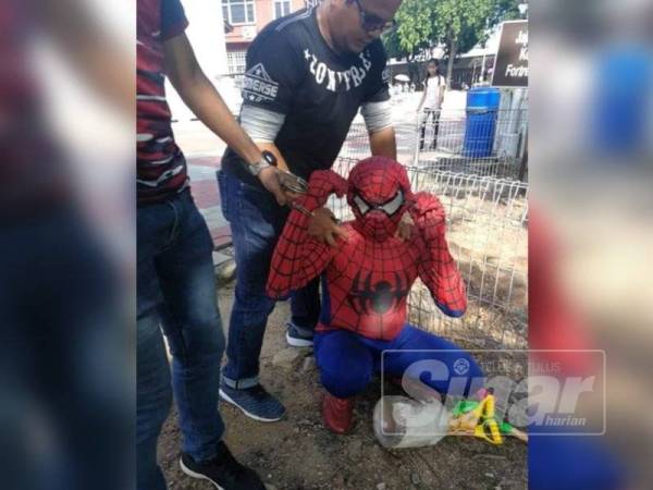 Anggota penguat kuasa JIM menahan 'Sipderman' yang didapati memakai kostum adiwara itu bagi mendapatkan wang dengan cara mudah.