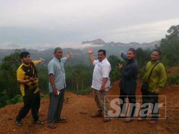 Mohd Zaid (dua dari kanan), Mansor (tiga dari kanan) dan pengunjung menunjukkan banjaran Gunung Pulai dan Baling yang boleh dilihat dari puncak Bukit AA.