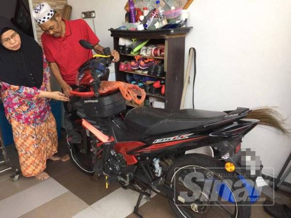 Masdi dan isteri, Saubiah Bujang, 52, menunjukkan perekat ‘mati itu pasti’ ditampal pada motosikal jenis Yamaha LC milik anak mereka yang maut dalam kemalangan pada 4 Julai lalu.