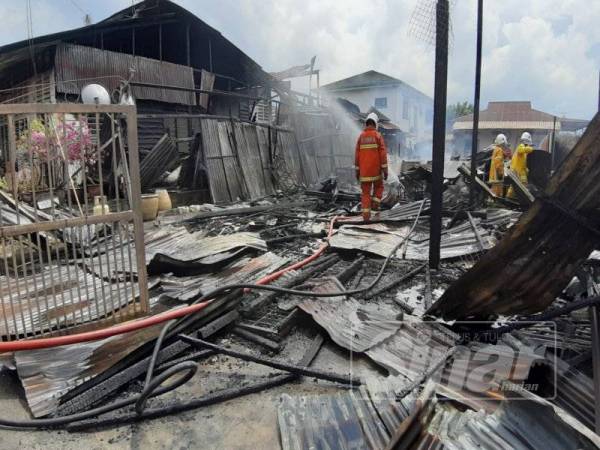 Anggota bomba melakukan operasi pemadaman sebuah rumah yang hangus 90 peratus dalam kejadian di Kampung Tawas hari ini.