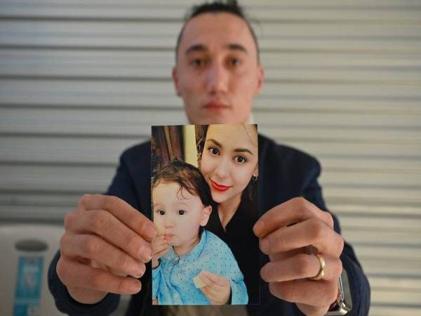 Sadam Abdusalam memegang gambar isterinya, Nadila Wumaier dan anak lelaki mereka Lutifeier. - Foto AFP