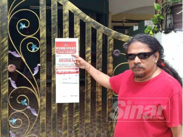 Kalaikumar menunjukkan pelekat peringatan bayaran cukai taksiran yang diletakkan di pagar rumah penduduk.