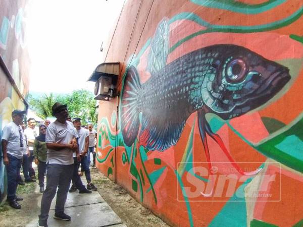 Muhammad Bakhtiar melihat mural berimej ikan laga yang dilukis di Flat Lily hari ini.