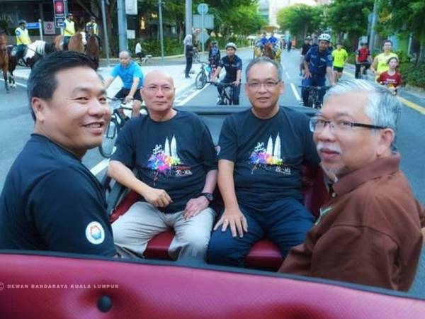 Nor Hisham (dua dari kiri) dan Mansor (dua dari kanan) menaiki pedati semasa program Car Free Morning di Dataran DBKL, Jalan Raja Laut hari ini.