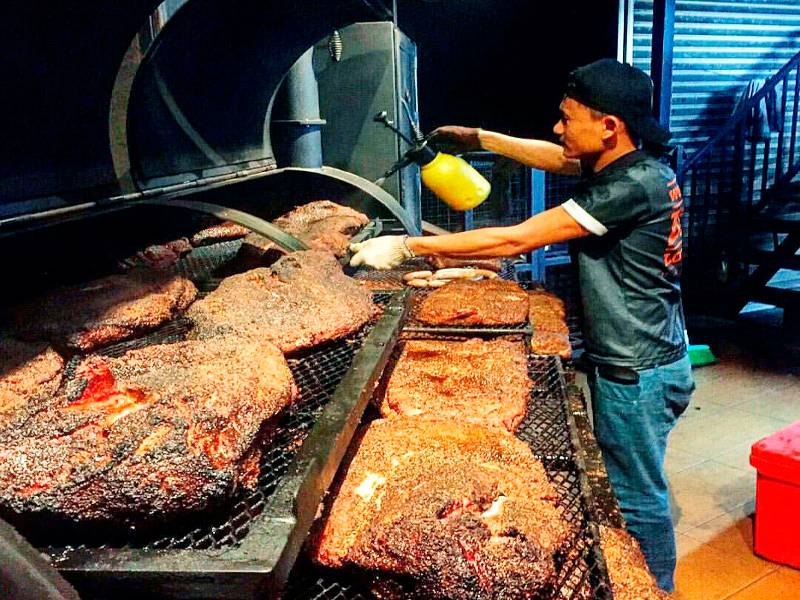 Seorang pekerja sedang menyalai daging.