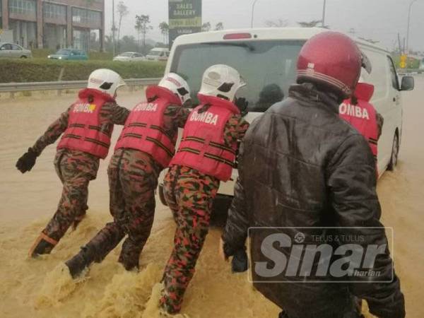 Anggota bomba membantu mengalihkan beberapa buah kenderaan yang terperangkap dalam banjir kilat di Jalan Rawang menghala Batu Arang di sini petang tadi.