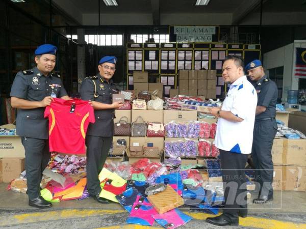 Muhammad Zikril (dua, kanan) menunjukkan barangan tiruan yang dirampas dan akan dilupuskan di Stor Simpanan Ekshibit Bukit Raja di sini hari ini.