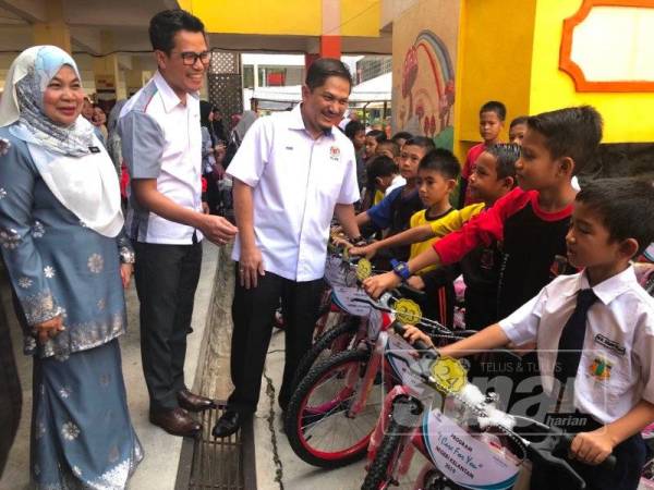 Amir Zakri (tiga dari kiri) menyampaikan basikal kepada 53 murid dari empat sekolah di SK Kedai Buloh 2 hari ini.