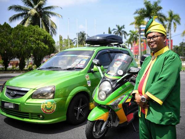 Peminat bola sepak Kedah Mohd Rizal Ismail, 44, memakai busana tradisional Melayu berwarna hijau kuning dan bergambar bersama kenderaannya yang dicat dengan warna yang sama sebagai tanda sokongan padu terhadap skuad Lang Merah hari ini. - Foto BERNAMA