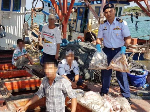 Rashidilhadi (kanan) memeriksa hasil tangkapan ikan daripada dua bot yang ditahan di Jeti Zon Maritim Kemaman hari ini.