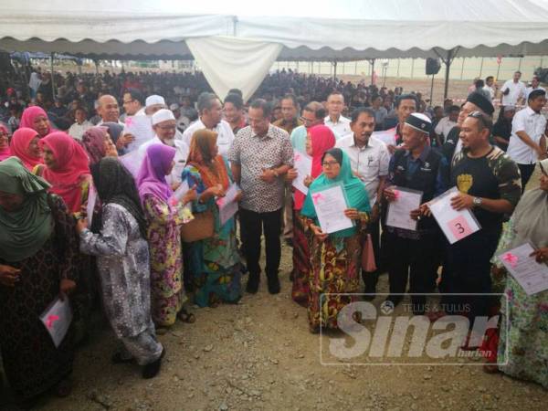 Ahmad Samsuri (tengah) bersama penerima pada majlis pelancaran Rumah Pangsa Mampu Milik di Tok Jembal hari ini.