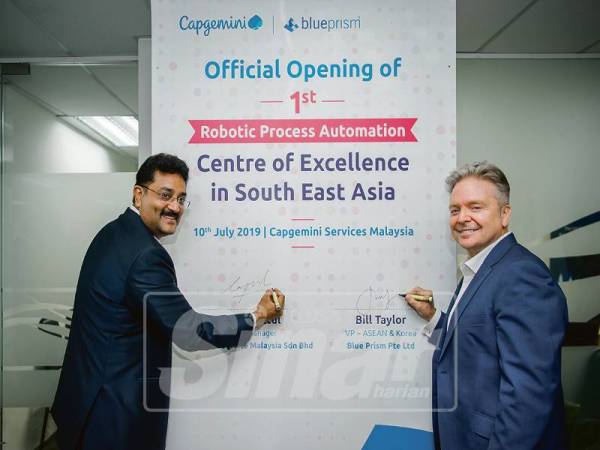 KETUA Capgemini Malaysia, Rajesh Kottul (kiri) dan Naib Presiden Blue Prism Korea dan Asean, Bill Taylor menandatangani simbolik sempena pelancaran Malaysian RPA Center of Excellence.