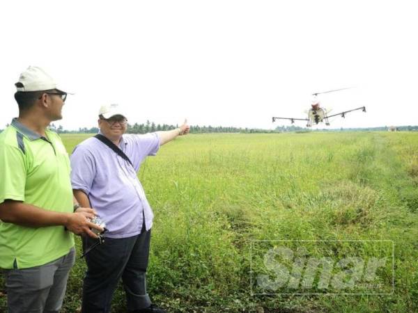 Wan Azrain (kanan) menunjukkan demonstrasi penggunaan dron bagi kegunaan sawah padi di Balai Raya Parit 12 Sungai Panjang.