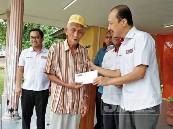 Mohd Hisyamuddin (kanan) menyampaikan sumbangan kepada penerima pada Program Kasih Peladang Kelantan di Lubok Jong hari ini.