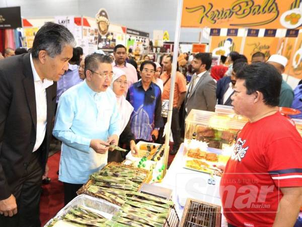 Salahuddin (dua, kiri) ketika melawat salah satu gerai jualan pengusaha di Ekspo Malaysia Fest, Ekspo Singapura, Changi, di sini hari ini.