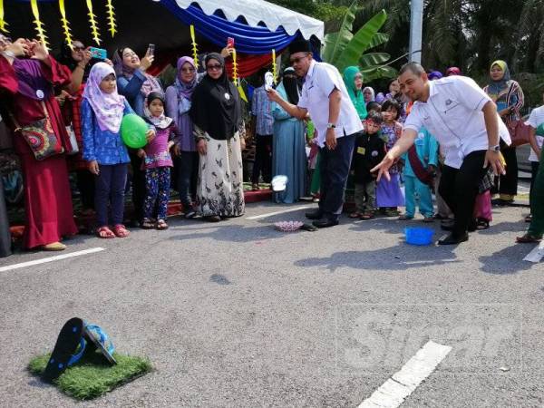 Dr Sahruddin (kanan) mencuba permainan tradisional sewaktu Program Karnival Perpaduan Di Hati Peringkat Negeri Johor 2019 di Simpang Renggam.