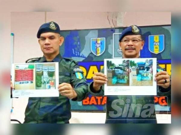 Ab Aziz (kanan) menunjukkan gambar barangan yang dirampas pada sidang media di Markas Taktikal Batalion 8 PGA Lubok Setol, Rantau Panjang hari ini.